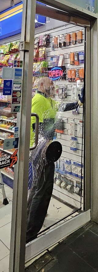 Mansour removing a shattered glass shop door at night